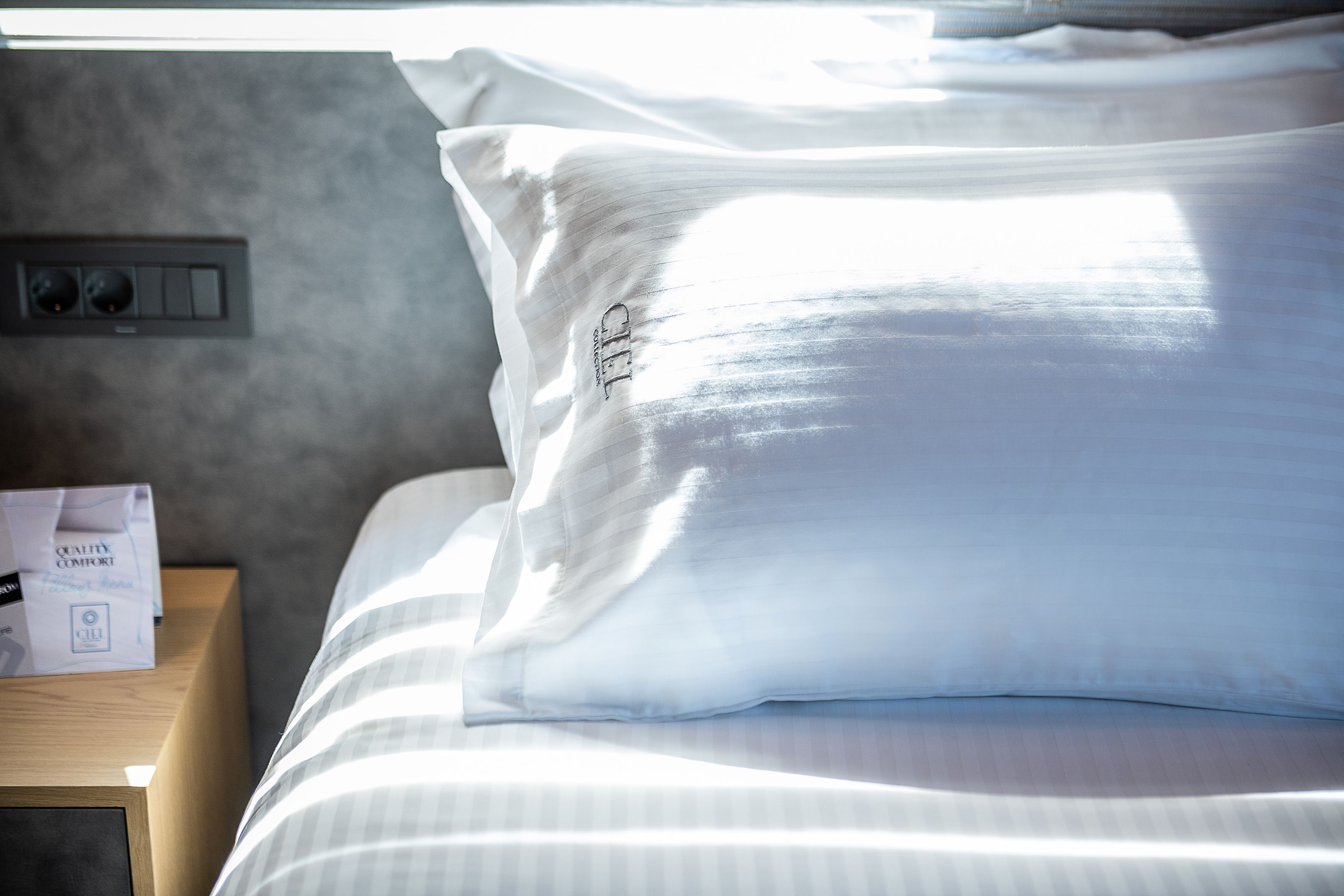 A neatly made bed with white bedding and a pillow with the text "GELL" on it.