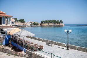 A seaside terrace with outdoor seating, a stone wall, and a view of the sea. - Ciel Collection Suites (Chania)
