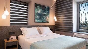 Una habitación de hotel moderna con una cama bien hecha, un cuadro abstracto grande en la pared y una ventana con persianas.
