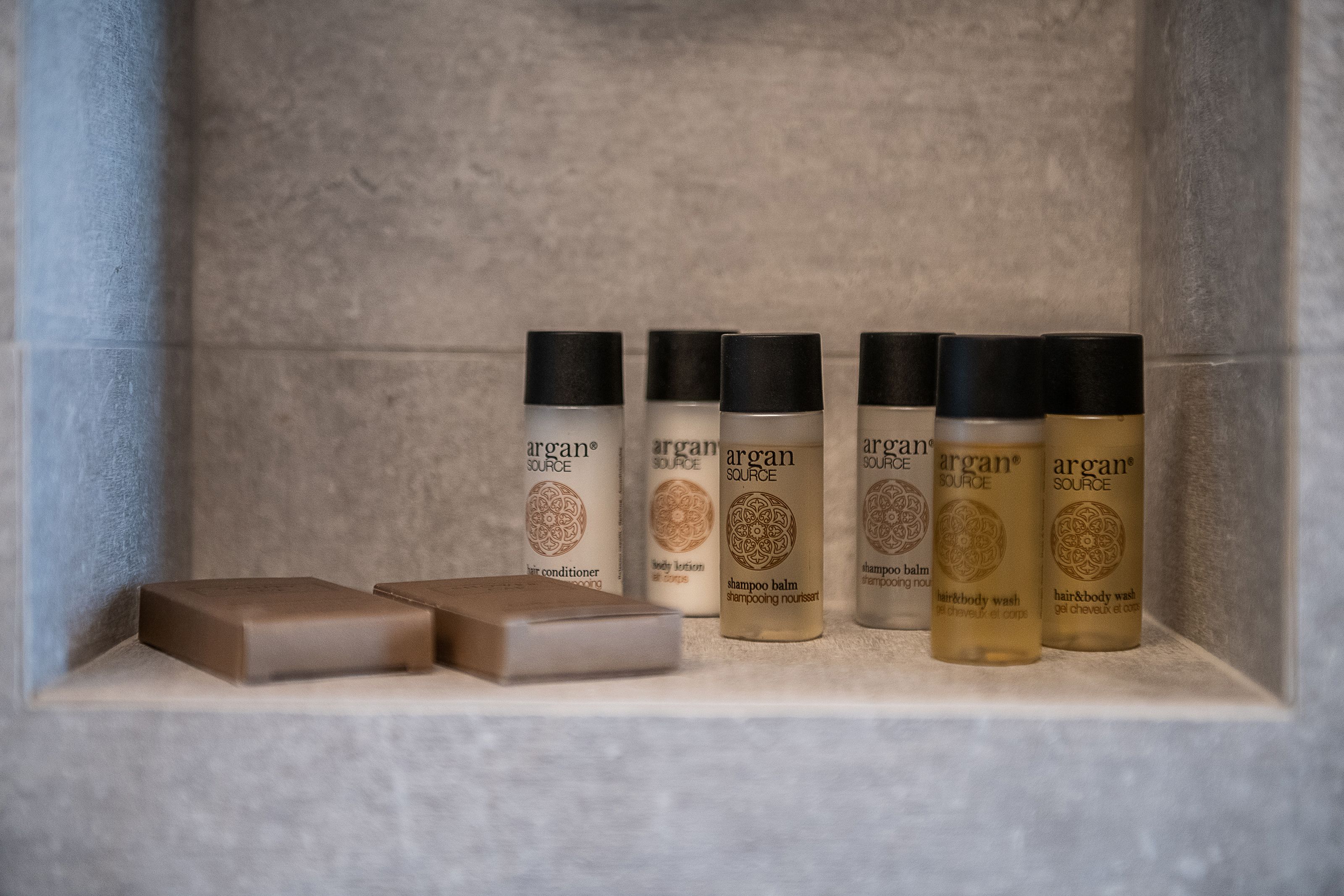 A shelf with various Argan Source products including body lotion, shampoo, and hair and body wash.