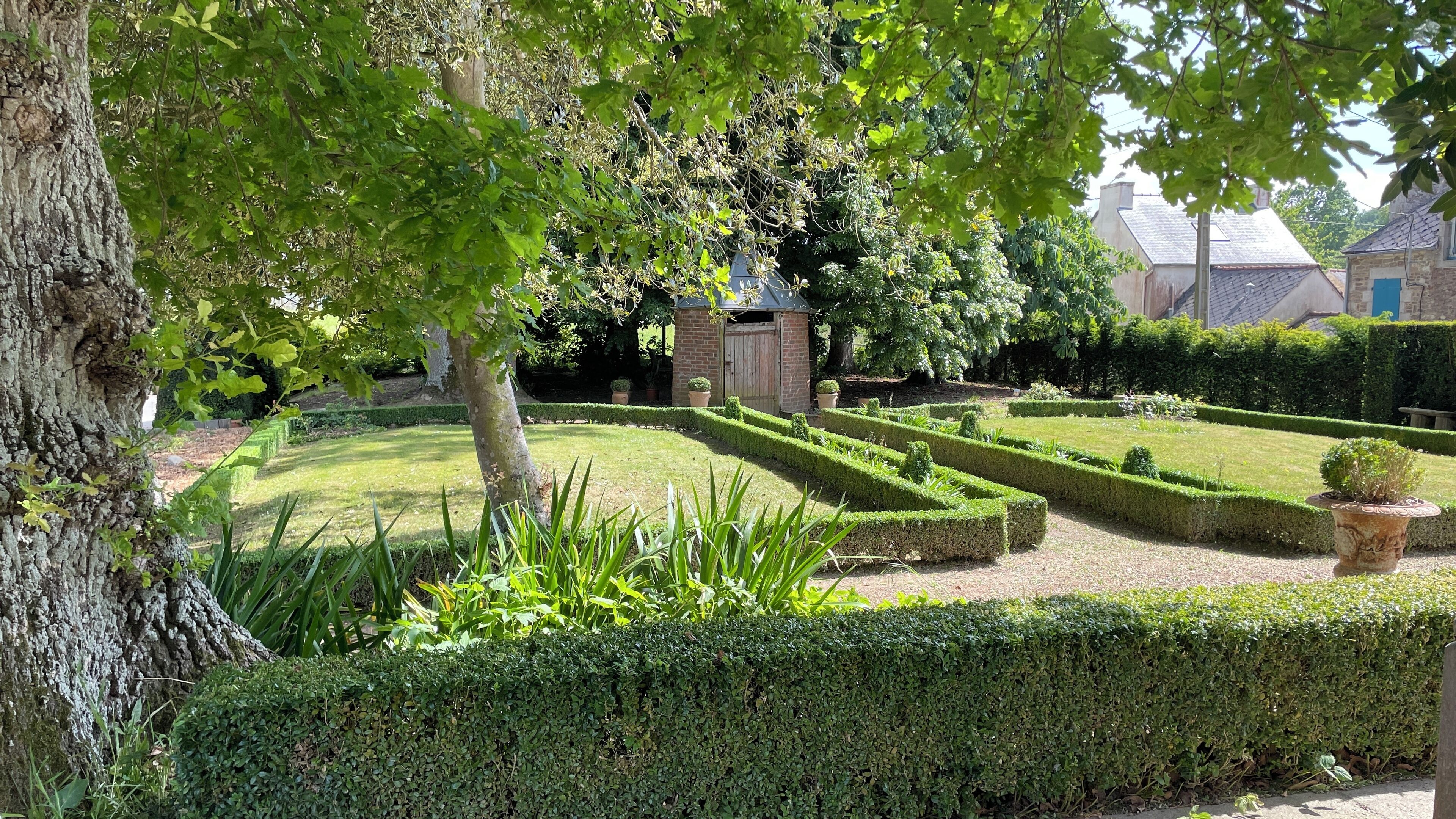 A well-maintained garden with neatly trimmed hedges and a small brick structure.