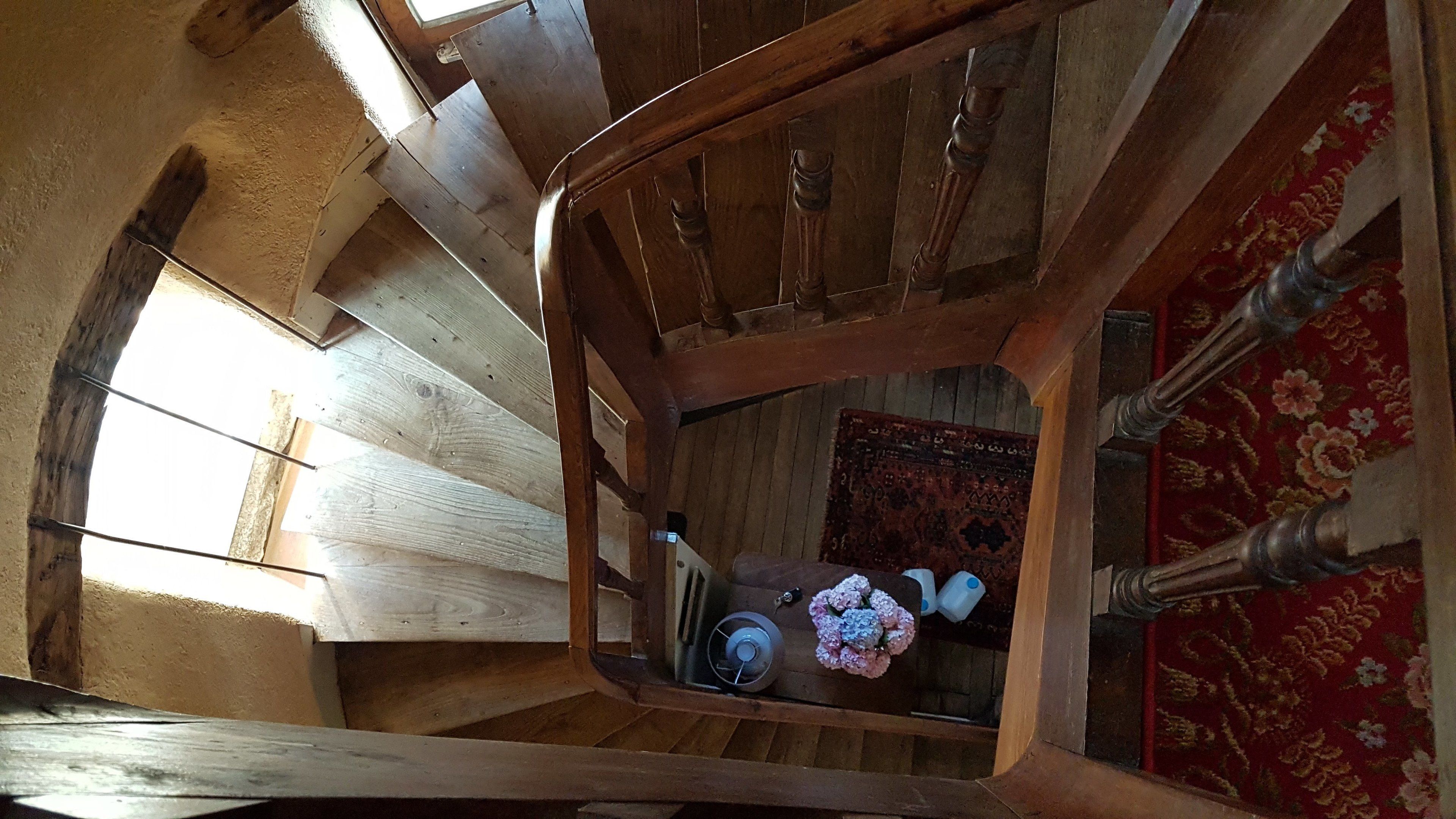 A wooden staircase with a view of a room below.