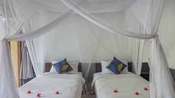 Una habitación con dos camas, cada una con ropa de cama blanca y almohadas decorativas azules.