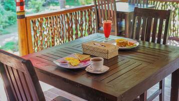 Una mesa de madera con alimentos para el desayuno, como tostadas, huevos revueltos y un batido.