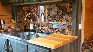 Une cuisine avec des meubles de rangement en bois, un évier en acier inoxydable et un plan de travail en bois.