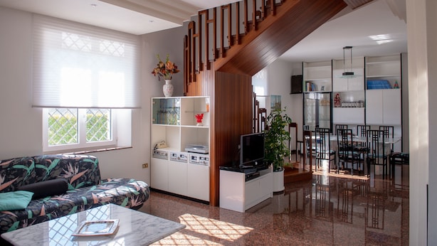 Una sala moderna con un sofá, una mesa de centro, un televisor y una escalera.