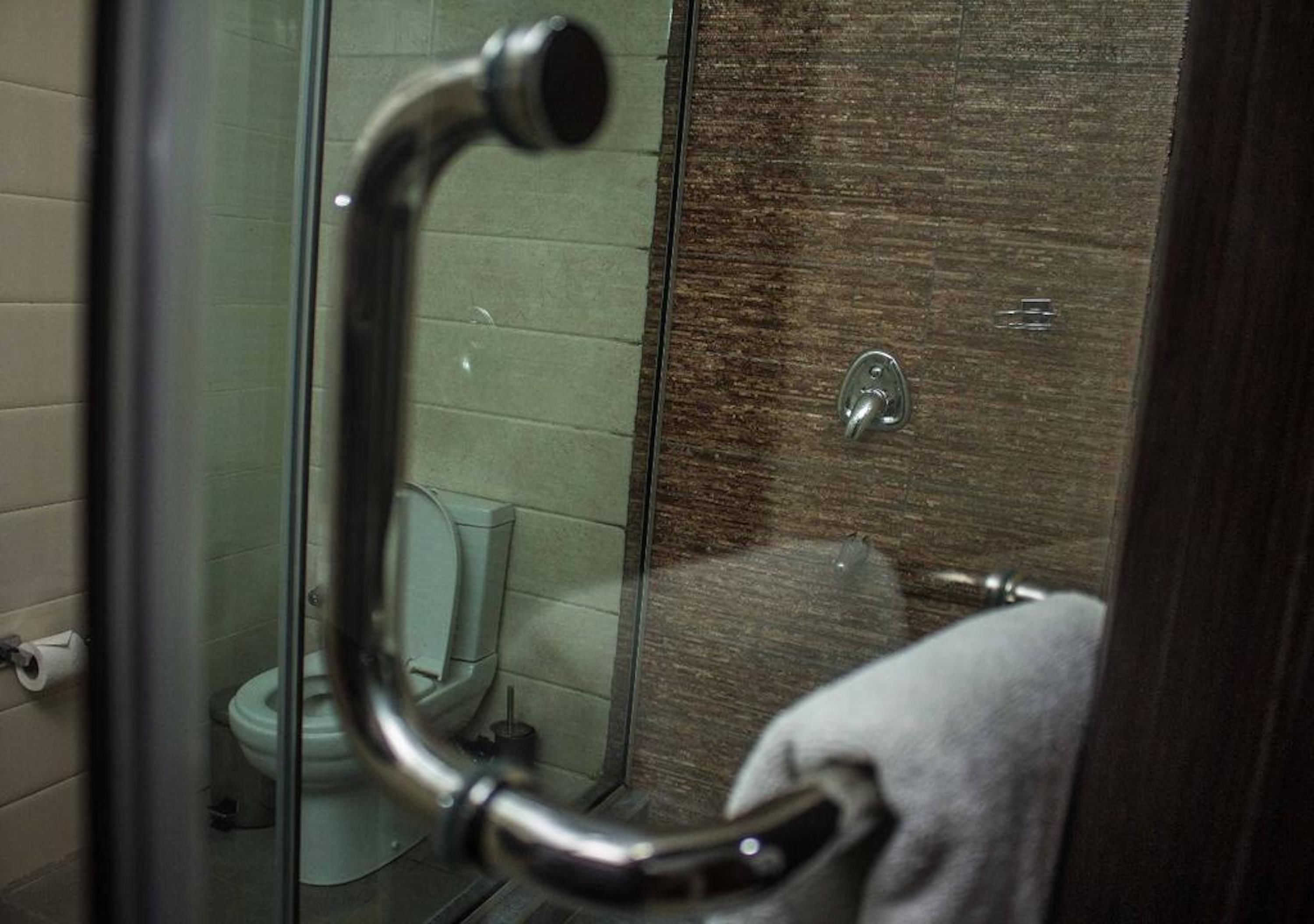 Un baño con cabina de ducha de vidrio, un inodoro y un perchero para toallas.