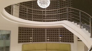Un interior moderno con una escalera curva, un sofá verde y una lámpara de techo original.