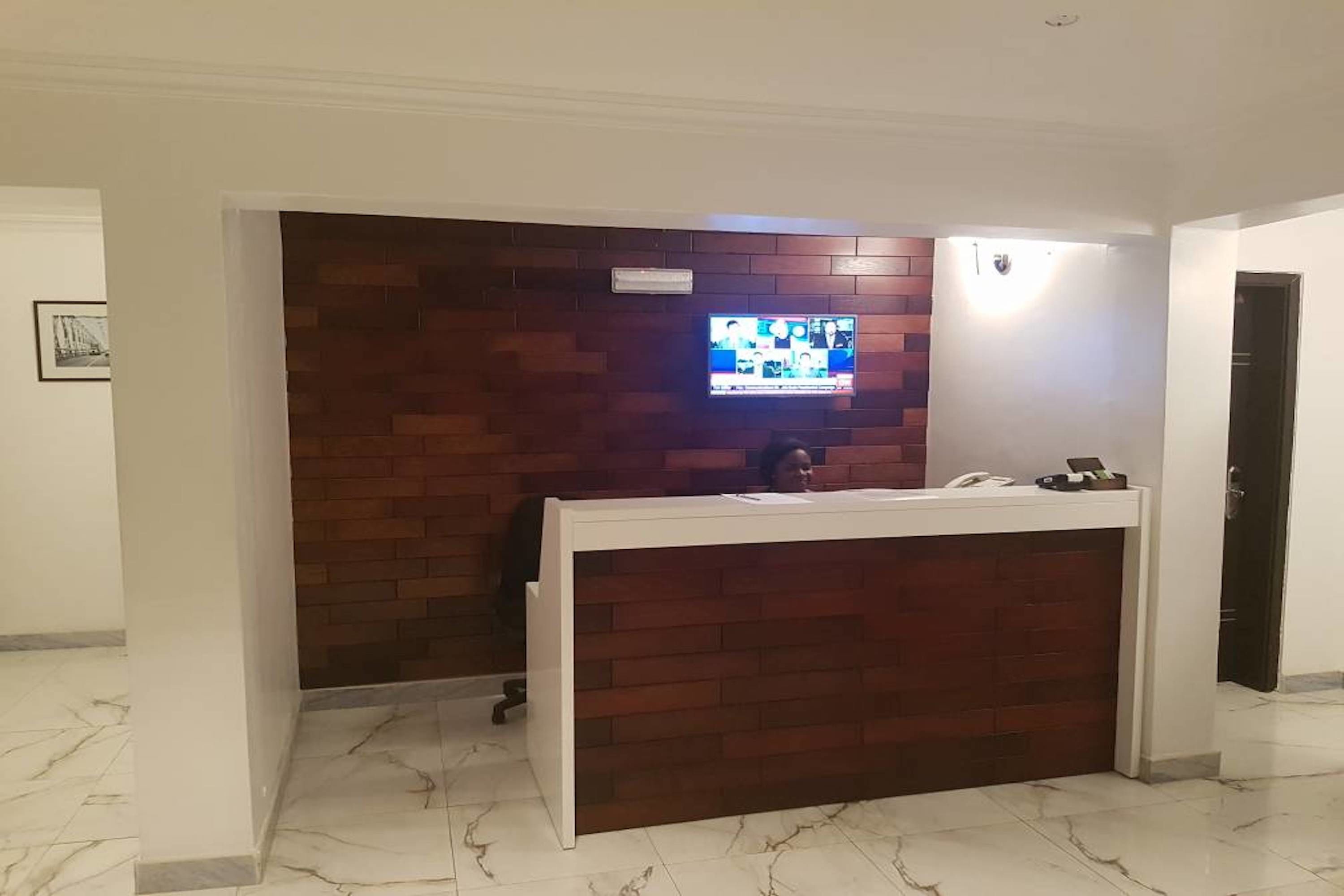 A reception desk with a television mounted above it, a phone, and a small table with a phone and a notepad.