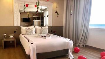 Quarto de hotel com uma cama grande, televisão e vista para o mar.
