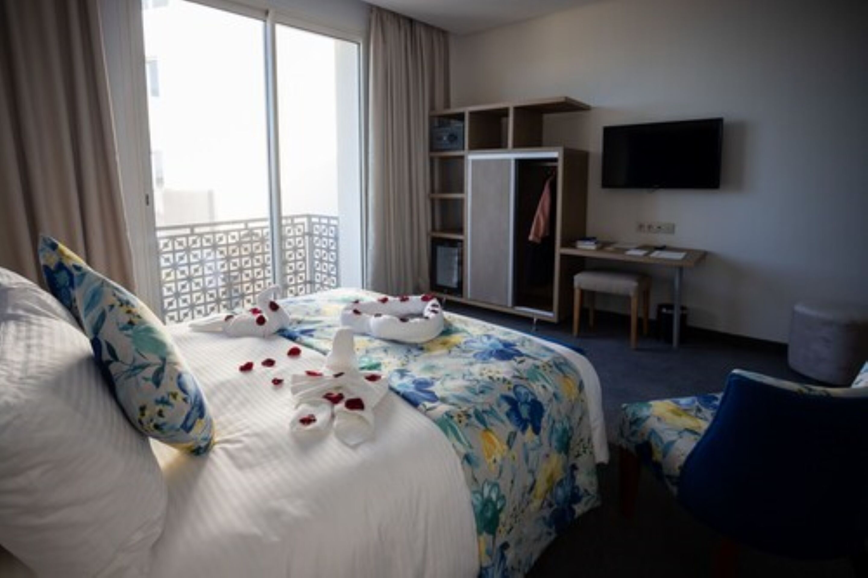 A hotel room with a bed, a desk, a wardrobe, and a TV.