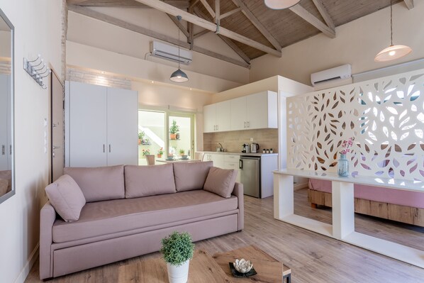 A modern living room with a beige sofa, a wooden coffee table, and a decorative plant. - Ancient Agora Apartments (Athens)