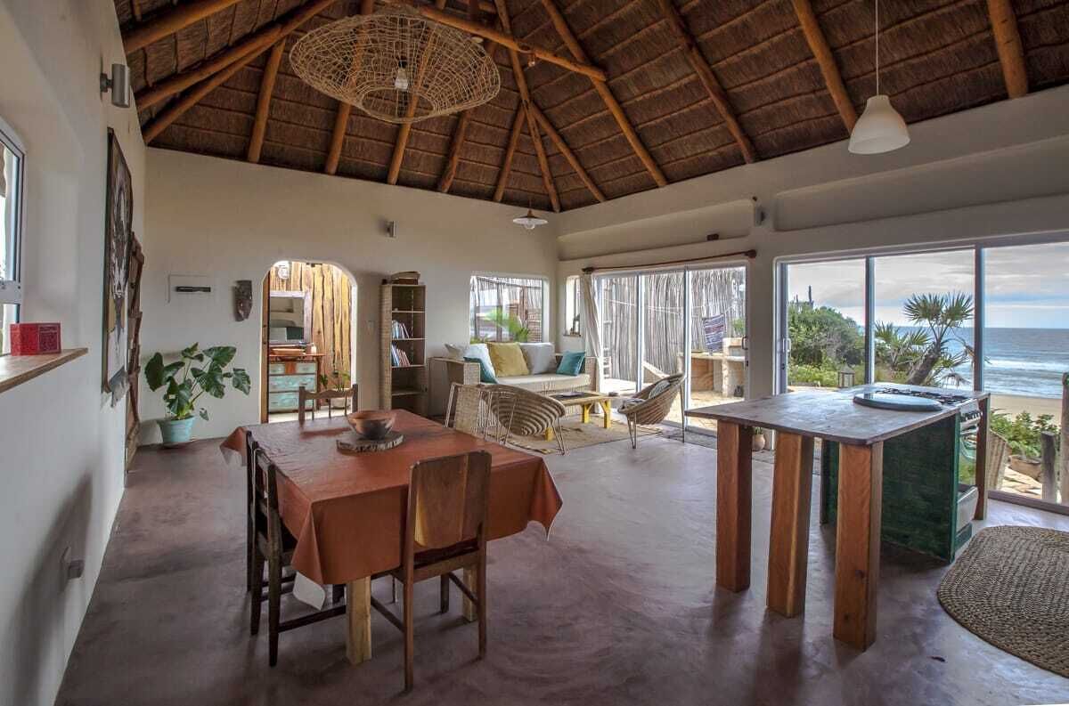 A spacious living area with a high ceiling, a dining table, and a view of the ocean.