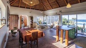 Una habitación amplia con una mesa de comedor de madera, un sofá y vista al océano.