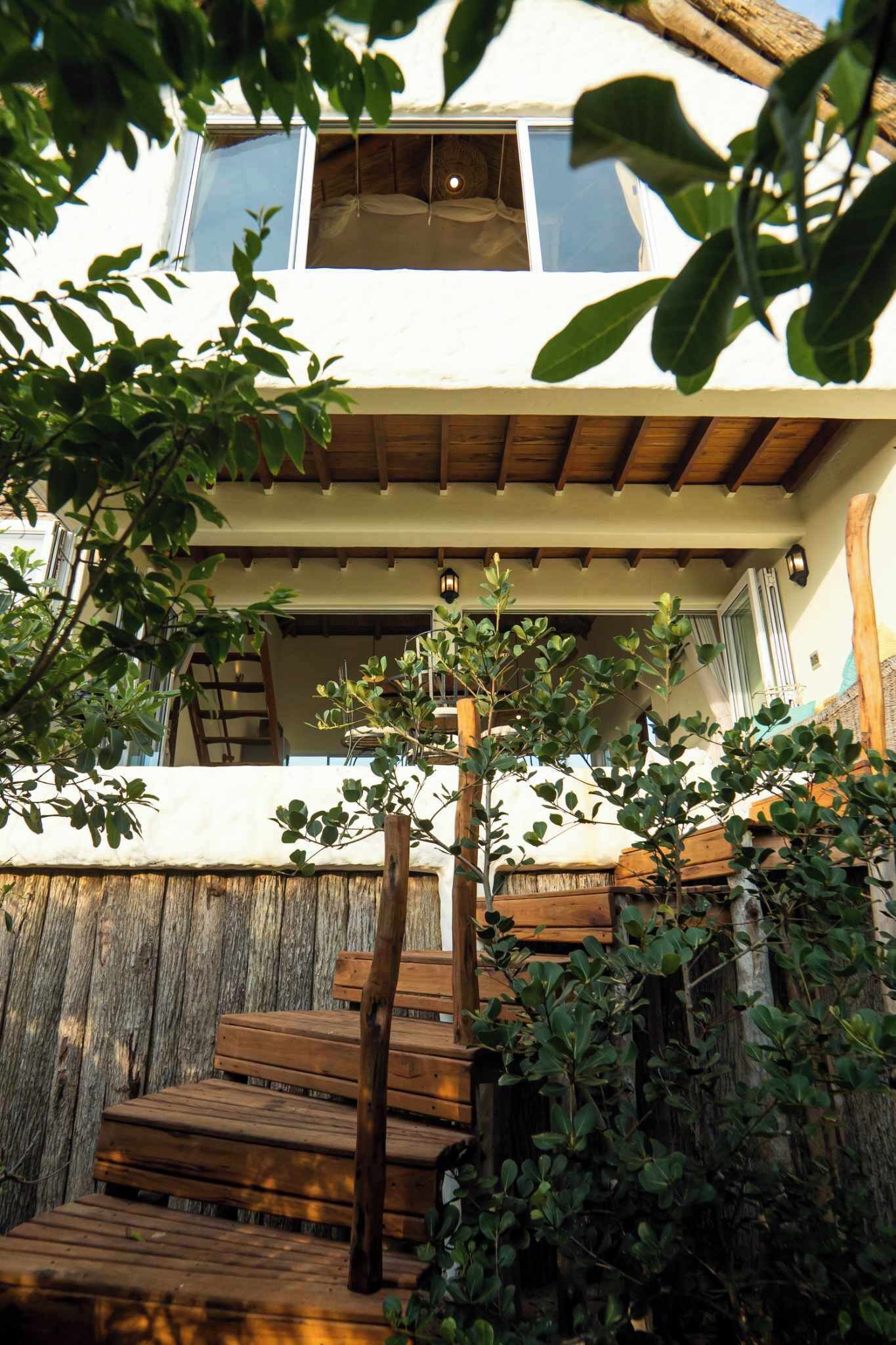 A wooden staircase leading to a white building with a window.
