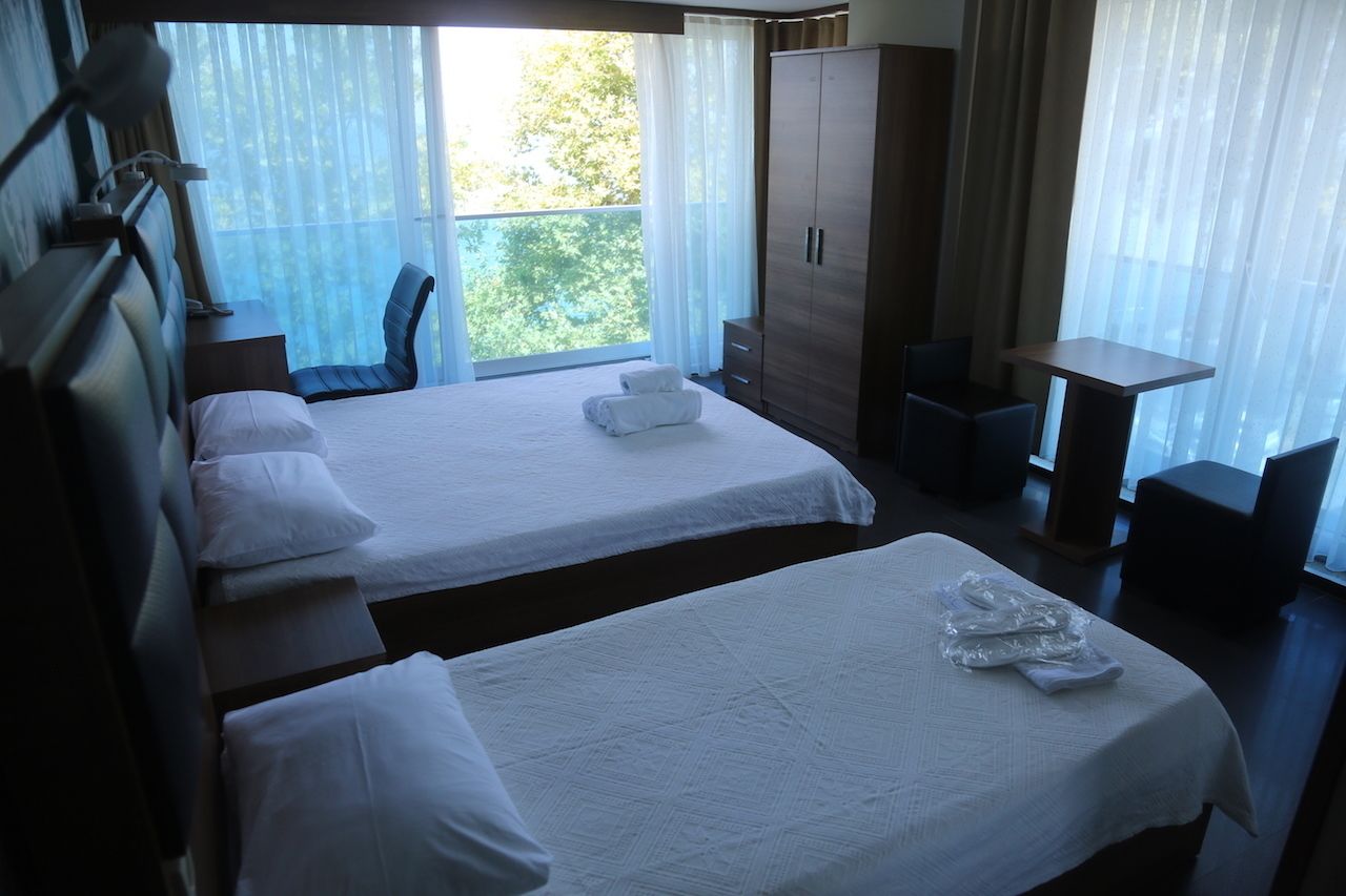 A hotel room with two beds, a desk, a chair, and a wardrobe.