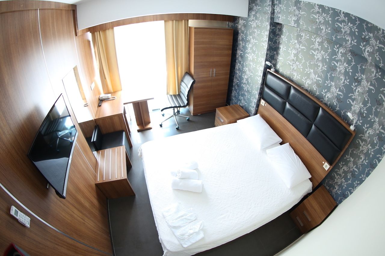 Habitación de hotel pequeña con cama, escritorio, silla y televisor.