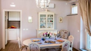 A dining area with a round table, chairs, a chandelier, and a cabinet with glass doors. - Casale di Vera (Cortona)