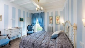 A bedroom with a bed, a chair, a dresser, and a window with curtains. - Casale di Vera (Cortona)