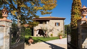 A stone building with a tiled roof, a gated entrance, and a well-maintained lawn. - Casale di Vera (Cortona)