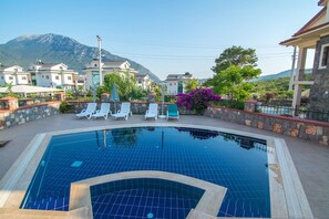 Una piscina al aire libre, sombrillas, sillones reclinables de piscina