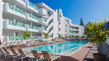 Een buitenzwembad, parasols bij het zwembad en ligstoelen