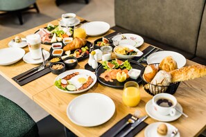 A breakfast buffet with various dishes, drinks, and utensils on a wooden table. - Hotel Wirthshof (Markdorf)