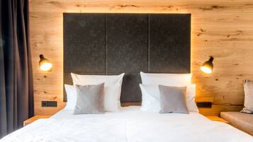 A neatly made bed with white linens and two pillows, a wooden headboard, and two wall-mounted lamps.