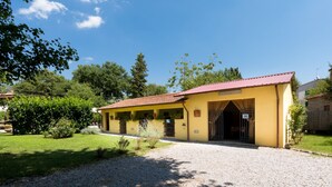 A yellow building with a red roof, a gravel driveway, and a small garden area. - Casa Lina (Castiglion Fiorentino)