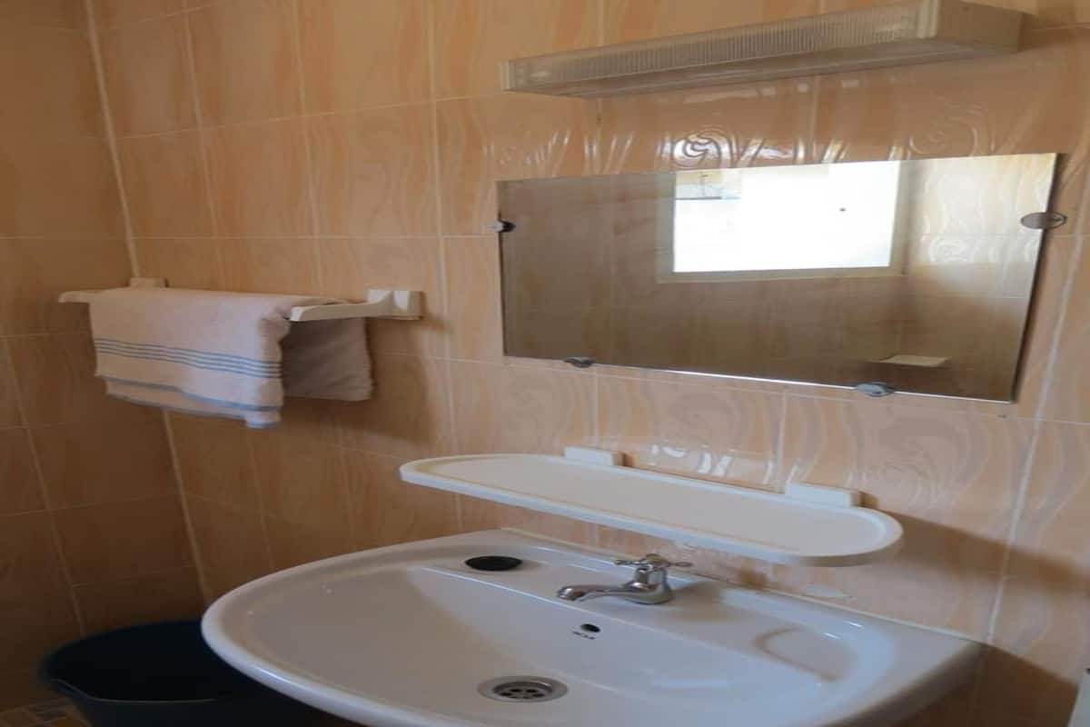 A bathroom with a sink, mirror, and towel rack.
