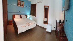 Un dormitorio con cama, mesita de noche, cómoda, espejo y una pequeña mesa con lámpara.