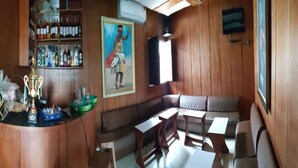 Una zona de bar con paneles de madera, una barra con un trofeo y un área de asientos con mesas y sillas.