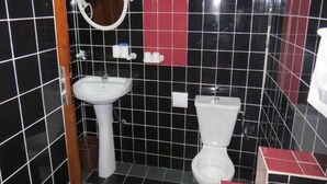 Un baño con lavamanos blanco, espejo y retrete.