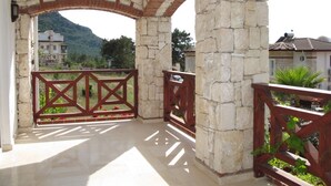 A covered outdoor area with stone columns and a wooden railing. - Anemon Solovilla (Fethiye)