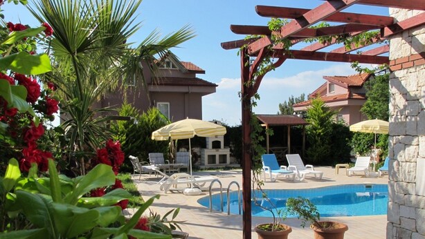 A pool area with lounge chairs, a pergola, and potted plants. - Anemon Solovilla (Fethiye)