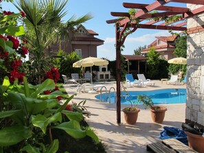 A pool area with lounge chairs, a pergola, and potted plants. - Anemon Solovilla (Fethiye)