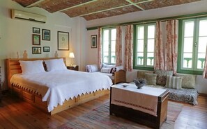 A room with a large bed, a sofa, a small table, and a window with curtains. - Nisanyan Hotel (Selçuk)