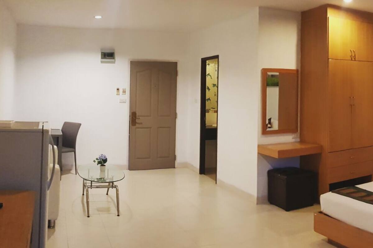 A hotel room with a bed, bedside tables, a desk, a chair, a TV, and a painting on the wall.
