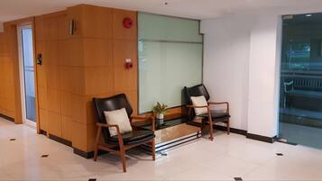 A reception area with two wooden chairs, a small table, and a potted plant.