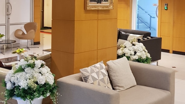 A lobby with a sofa, a framed portrait, and a vase of flowers. - Sena house Paholyothin30 (Bangkok)