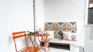 Un petit coin salon accueillant, avec un banc et une table, agrémenté d’un mur décoratif en carreaux et d’un simple mur blanc en arrière-plan.