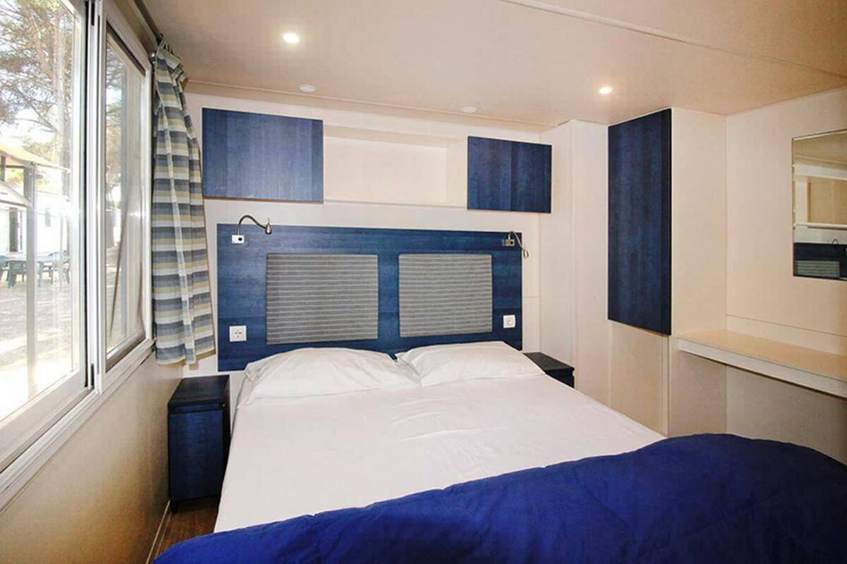 Ein Schlafzimmer mit Bett, einem Fenster mit Vorhängen und eingebauten Schränken.