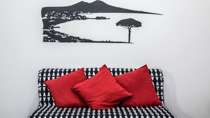 A wall with a black and white landscape print and a patterned sofa with red cushions. - San Cosmo's Flat Naples Centre (Naples)