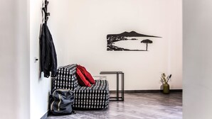 A modern room with a patterned sofa, a small table, a coat rack, and a wall art piece. - San Cosmo's Flat Naples Centre (Naples)