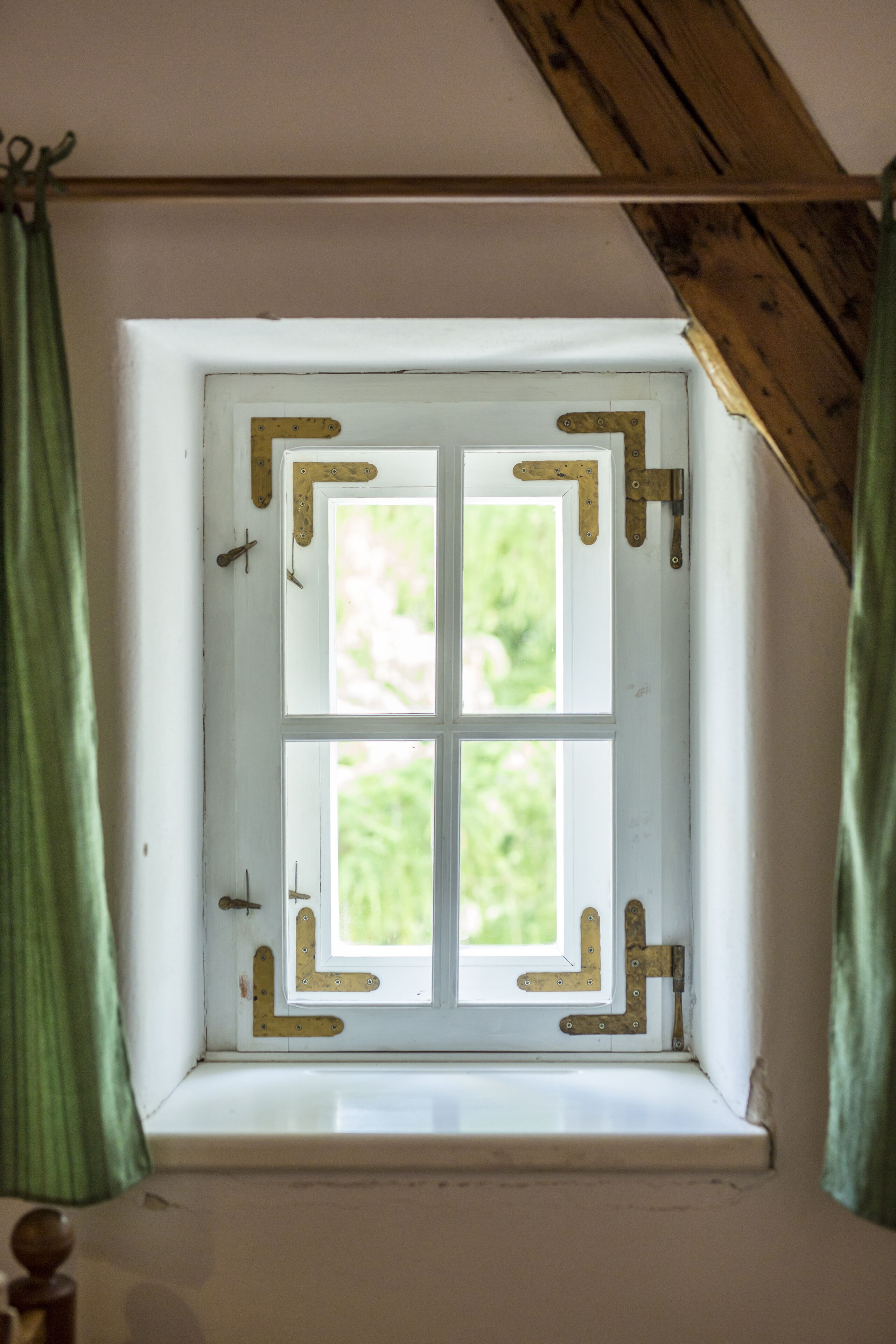 Una ventana con marco blanco y una viga de madera encima.
