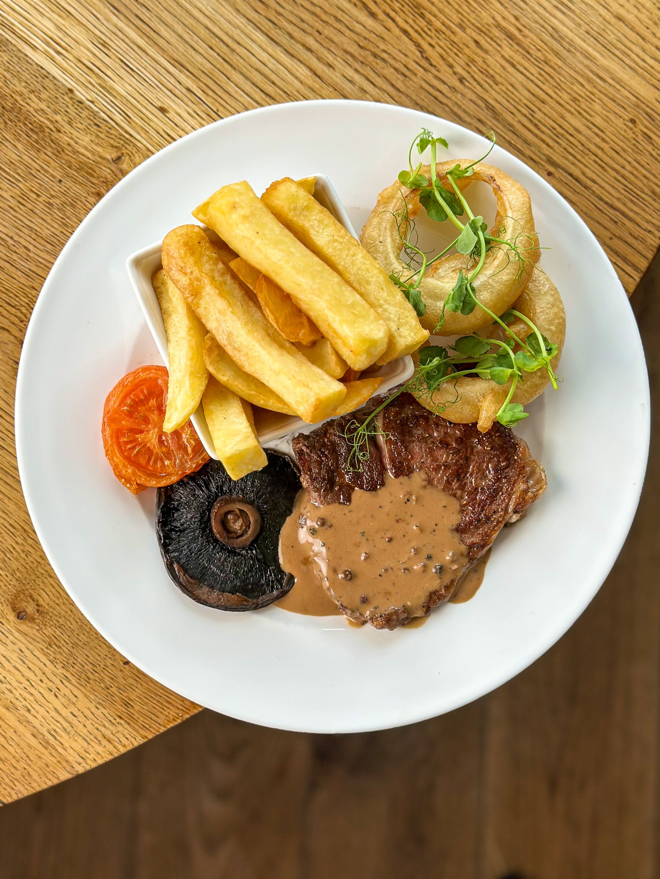 A plate with steak, fries, mushrooms, and a small salad.