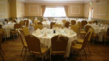 A banquet hall with round tables set for dining, equipped with chairs and table settings.