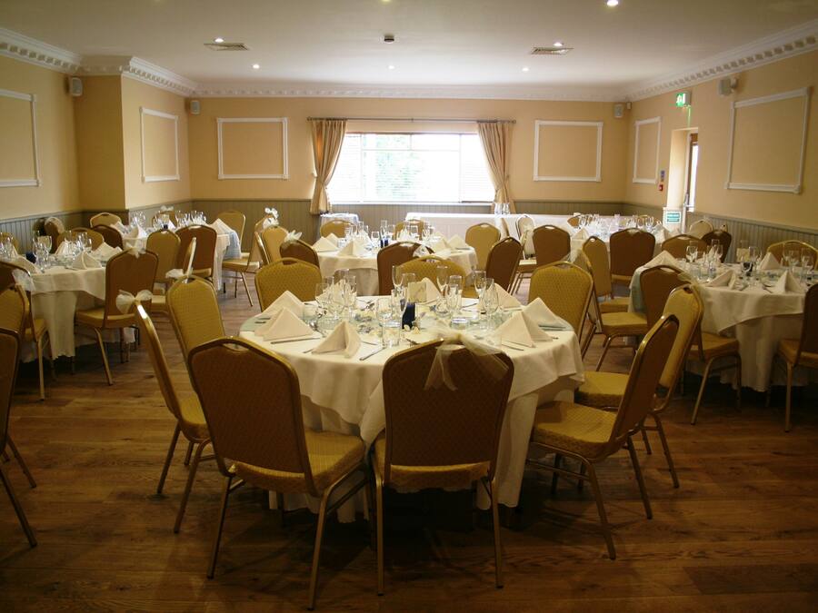 A banquet hall with round tables set for dining, equipped with chairs and table settings.