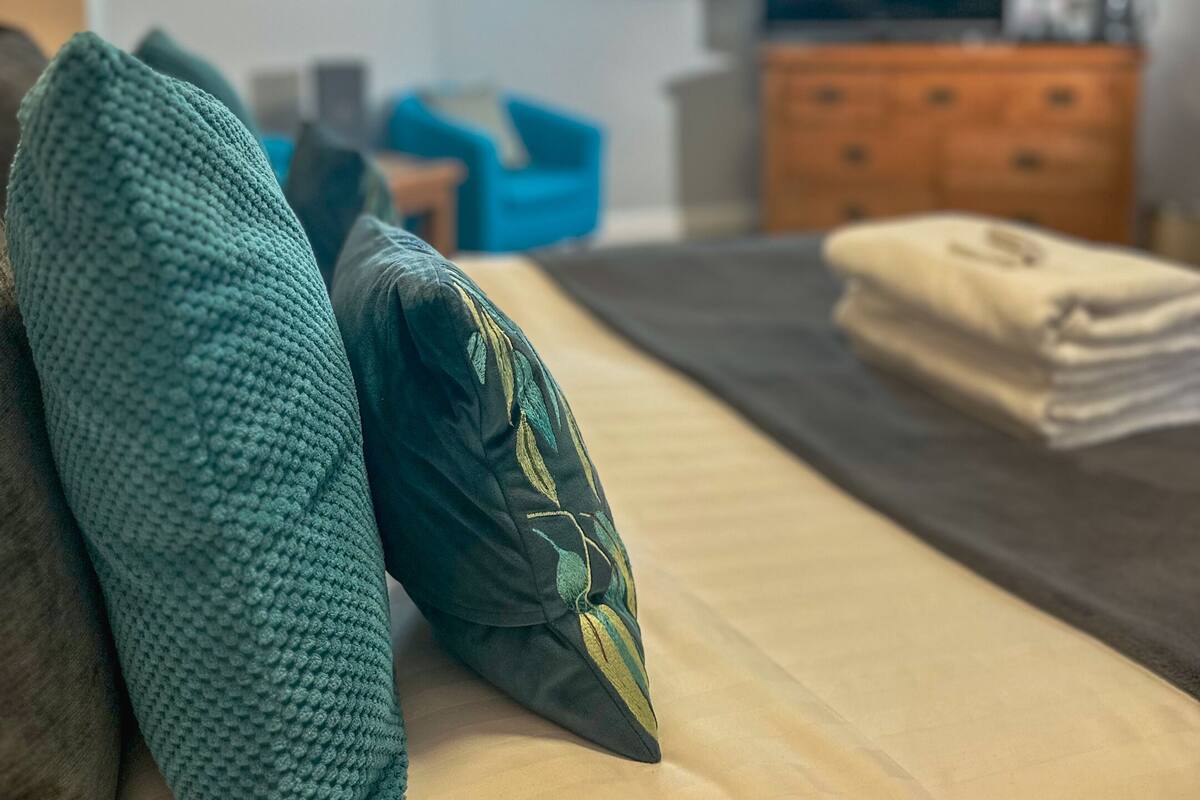 Ein gemütliches Schlafzimmer mit Bett, Kissen, einem Schminktisch und einem Fernseher.