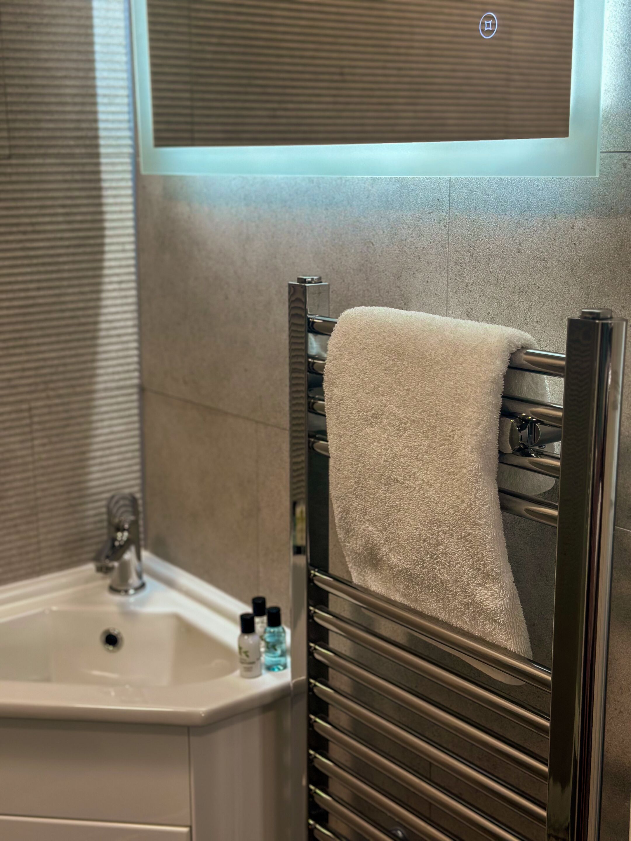 A bathroom with a sink, mirror, towel rack, and toiletries.